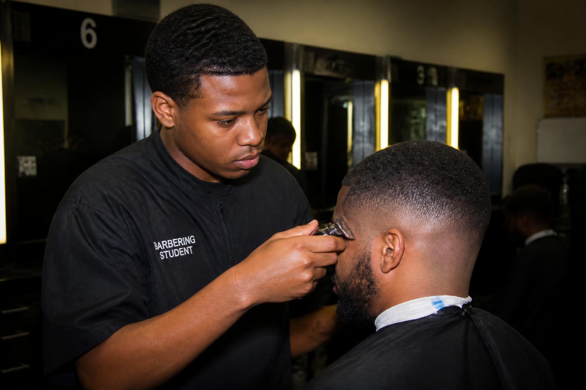 Barbering student completing a precision fade haircut under instructor supervision